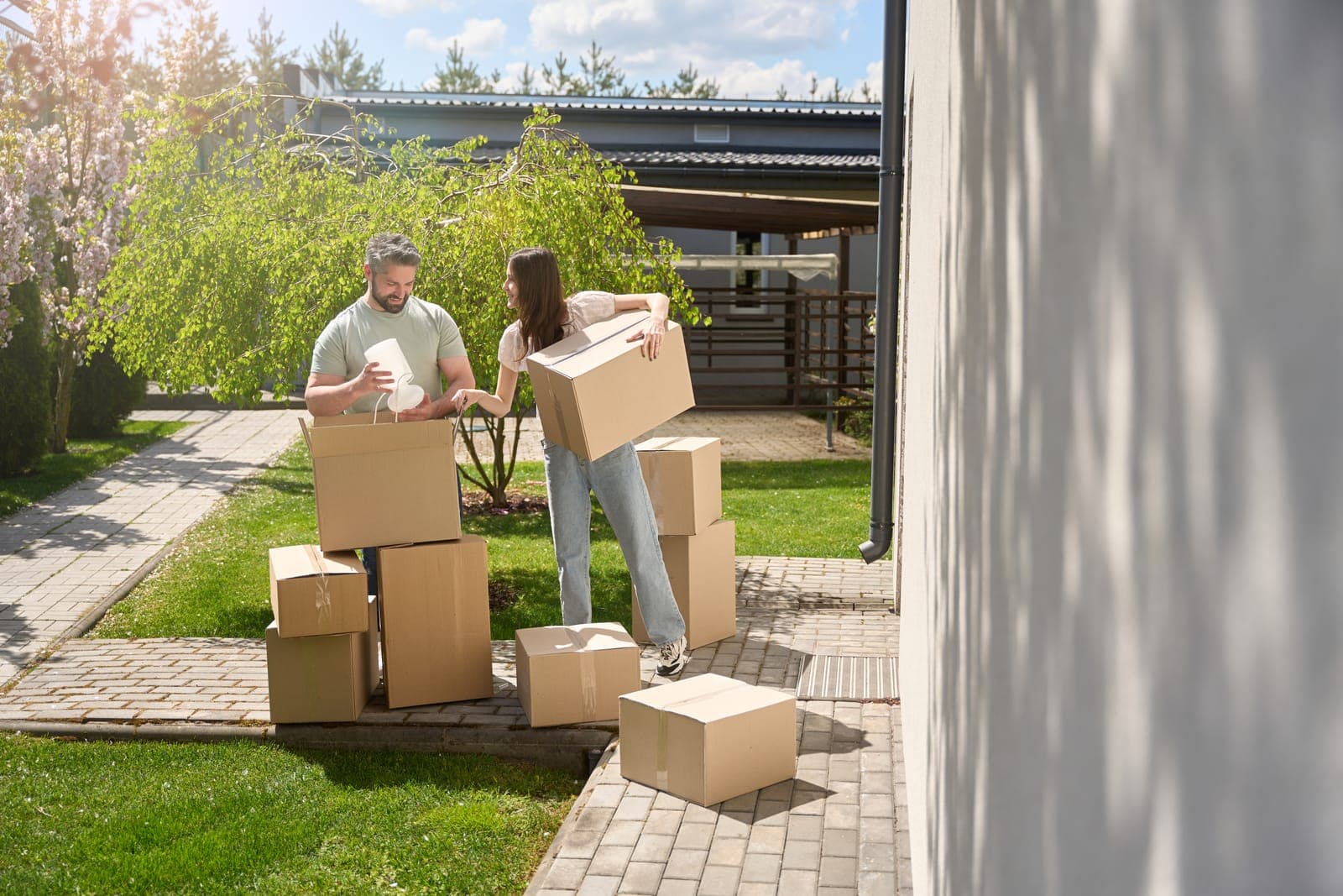 Couple Moving Cardboard Boxes in Sunny Backyard